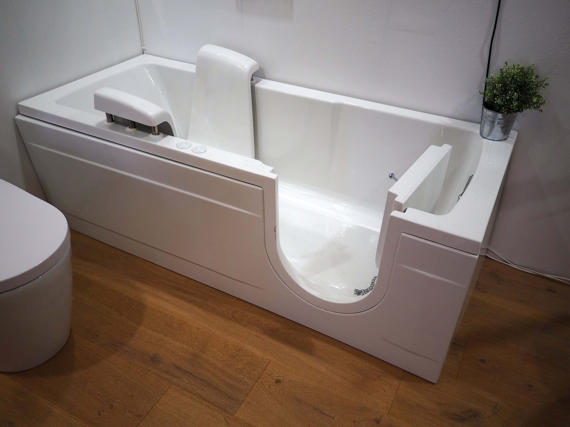 accessible bathtub in bathroom with wood floors next to toilet